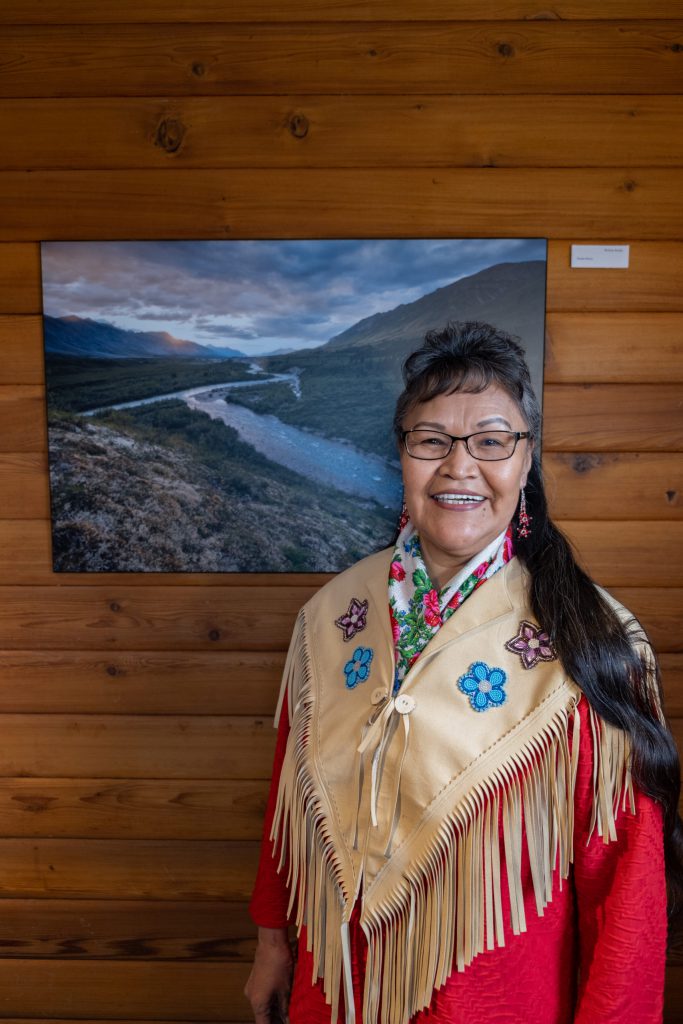 Award winner Lorrain Netro stands next to photo of the Peel Watershed located in the Yukon