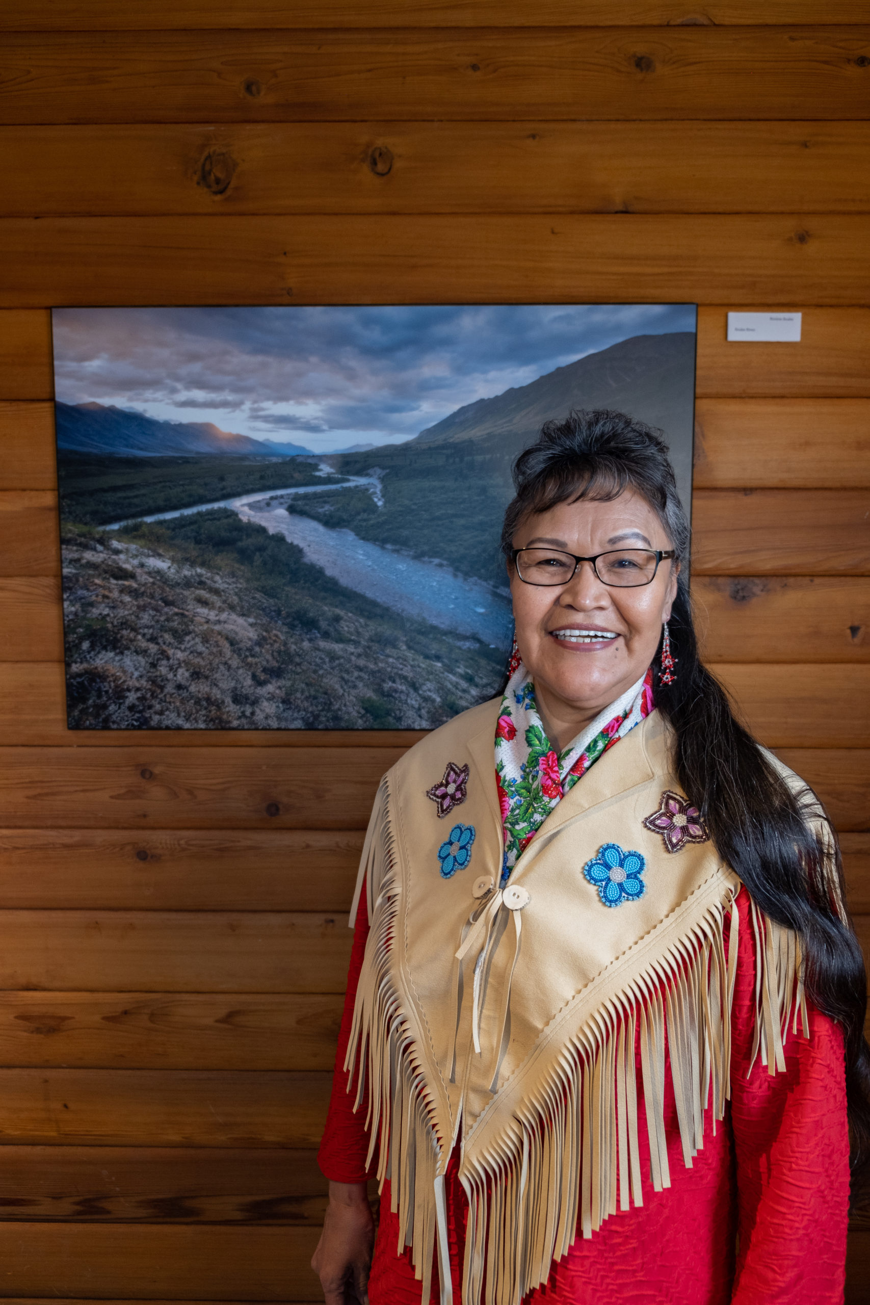 Award winner Lorrain Netro stands next to photo of the Peel Watershed located in the Yukon