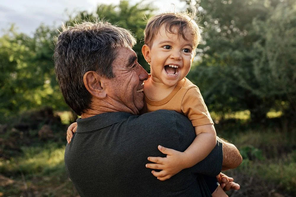 A man holding his grandson in his arms.
