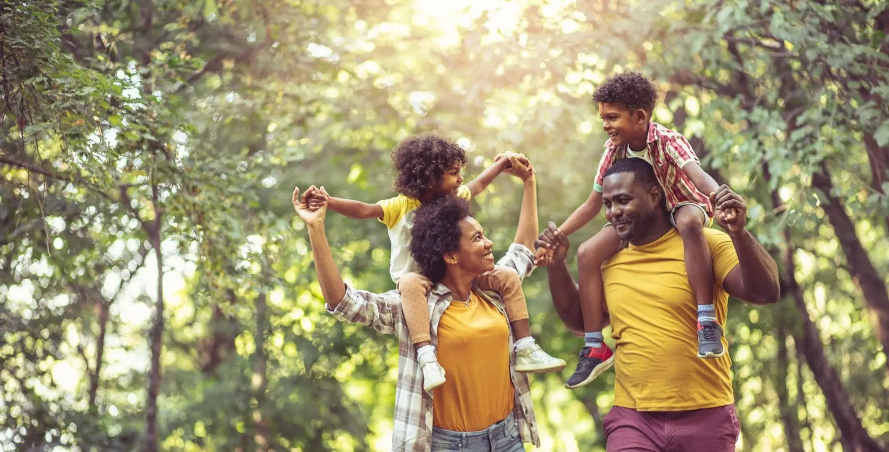 Parents walking in nature with their children on their shoulders
