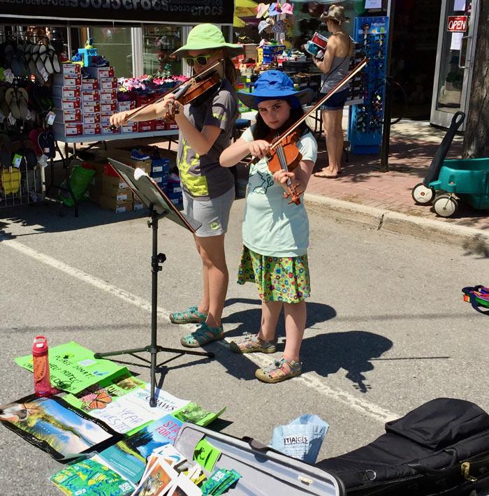 Two little girls playing violin in the street
