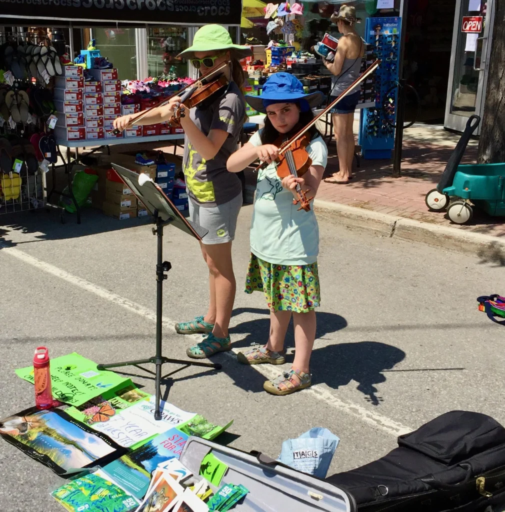 Deux petites filles jouant du violon dans la rue