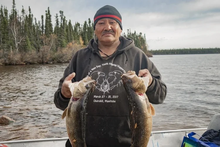 Man with fish next to the water