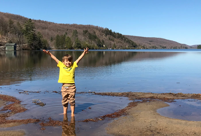 Young boy with his feet in the water on the shore of Meech Lake.