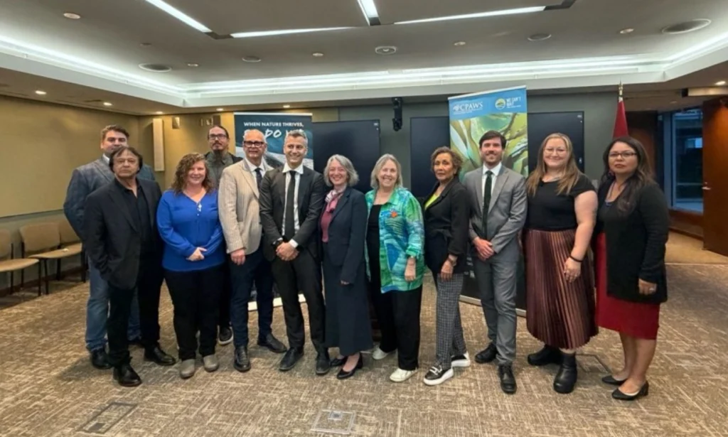 Speakers Mayor Spence and former Chief Shaw stand with event attendees, including Minister Julie Dabrusin (Environment, Climate Change and Nature); leader of the Green Party, Elizabeth May, MP; host, Patrick Weiler, MP. 
