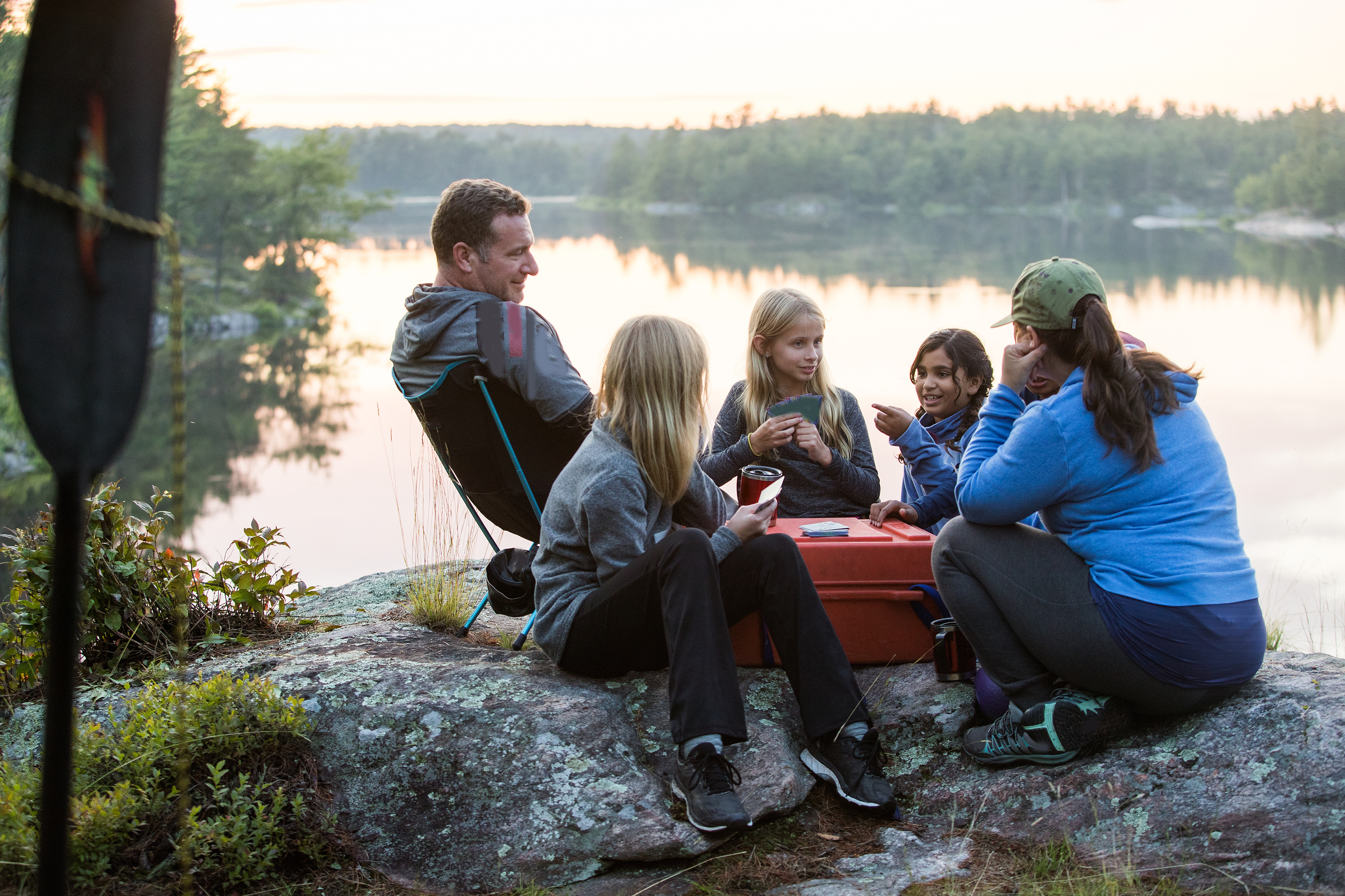 Family camping and playing cards by the water.