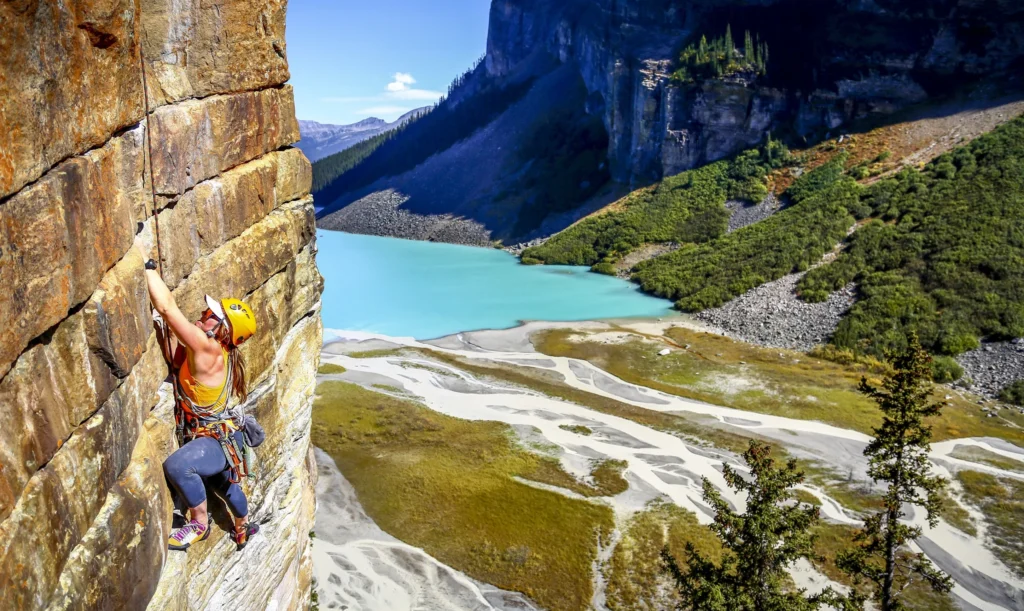 Women rock climbing beside Lake Louise.