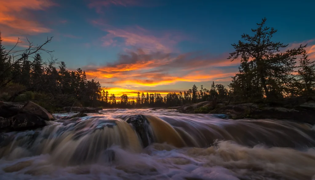 Waterfall in a river surrounded by boreal forest.